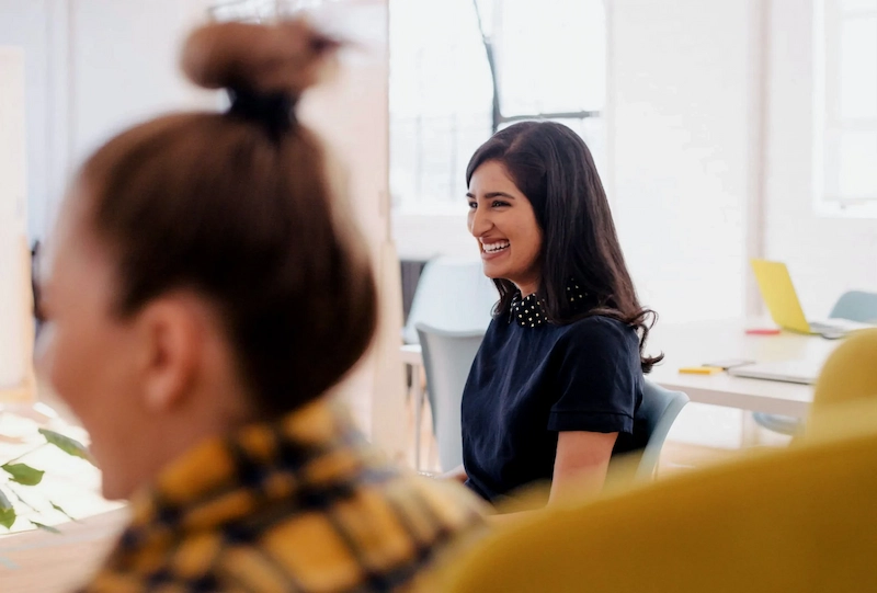 Femme souriante assise dans un bureau, dégageant une atmosphère professionnelle