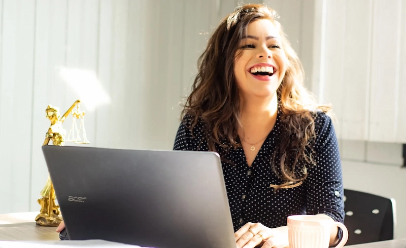 Femme souriante utilisant un laptop, exprimant joie et concentration